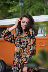 Beautiful young woman standing against bus