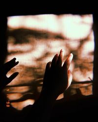 Close-up of silhouette hand on window
