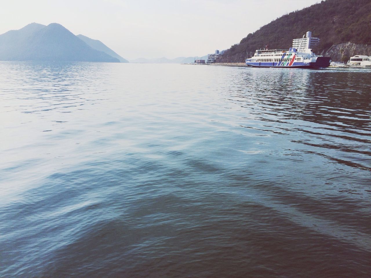 water, sea, mountain, waterfront, tranquil scene, tranquility, nautical vessel, rippled, scenics, beauty in nature, reflection, nature, sky, boat, lake, transportation, clear sky, idyllic, building exterior, calm