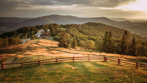 Scenic view of field by mountains against sky