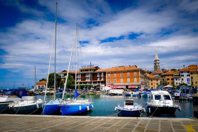 Sailboats moored at harbor against sky