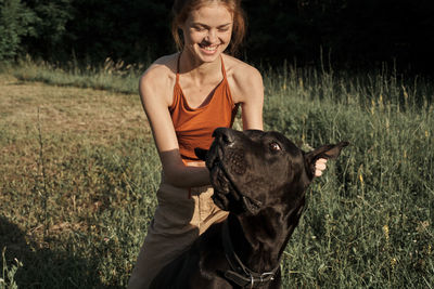 Portrait of woman with dog on grassy field