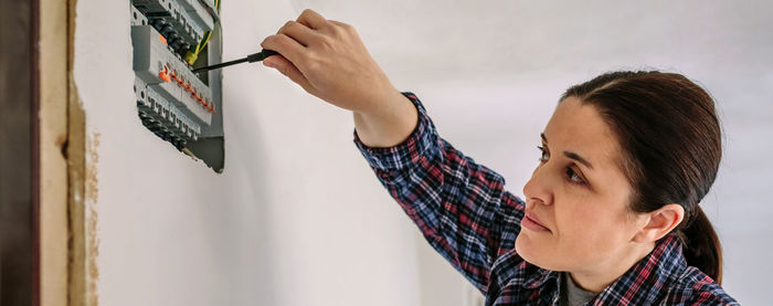 Woman working over electrical equipment on wall