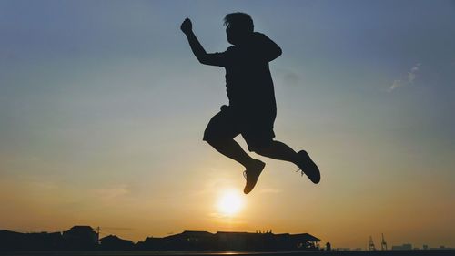 Silhouette man jumping against sky during sunset