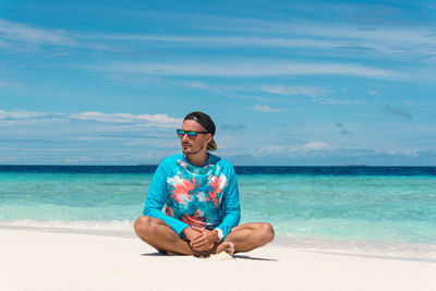Man wearing sunglasses at beach against sky
