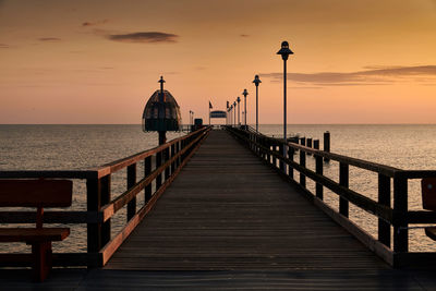 Pier over sea against sky during sunset