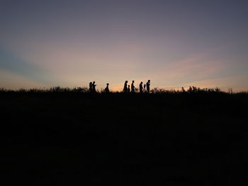 Silhouette people on field against sky during sunset