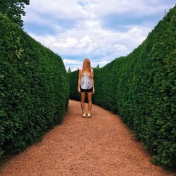 Rear view of woman standing on green landscape against sky