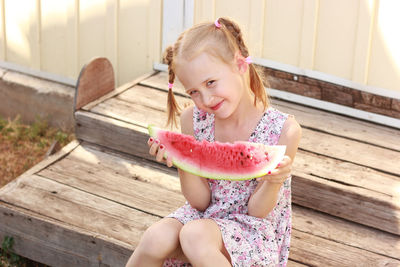 Smiling girl sitting on steps holding watermelon slice