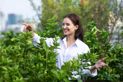 Portrait of young woman standing by plants