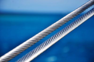 Close-up of metal rope against blue sea