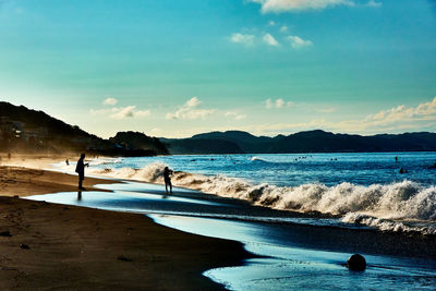 Scenic view of beach with people fishing against sky in the morning