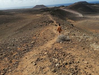 Rear view of man walking on dirt road