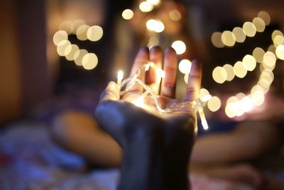 Close-up of hand holding illuminated candles