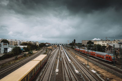 Railway tracks in city against cloudy sky