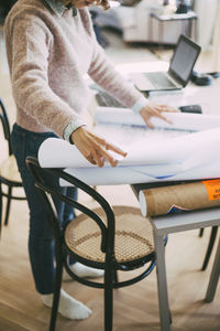 Woman working at home looking at blueprints