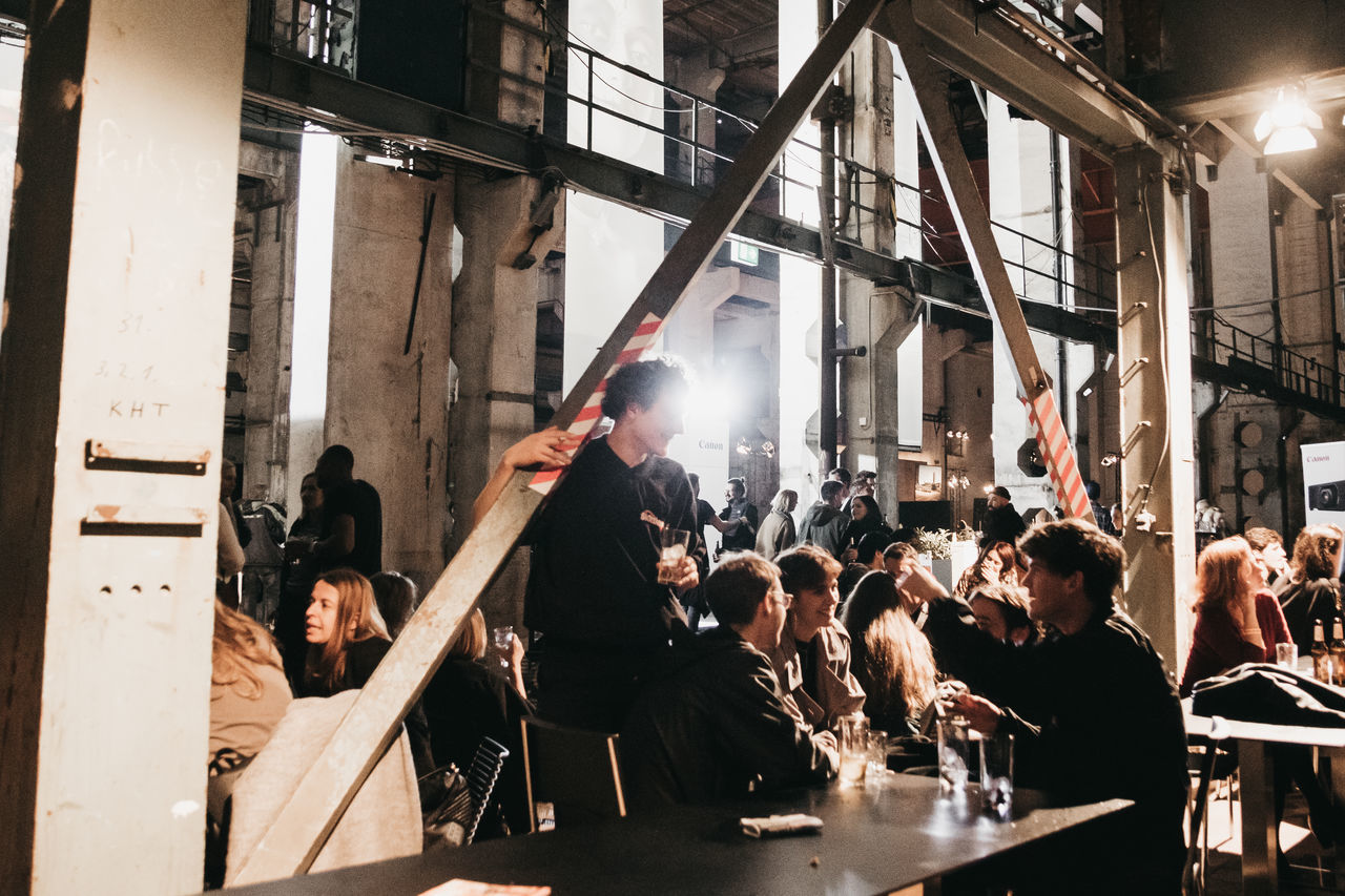 group of people, real people, large group of people, crowd, men, women, indoors, adult, occupation, arms raised, human arm, smoke - physical structure, illuminated, lighting equipment, architecture, lifestyles, standing, lens flare, young men