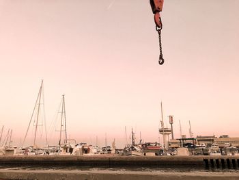 Sailboats moored on harbor against sky during sunset