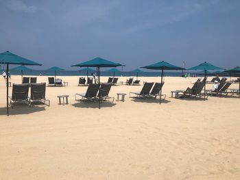 Chairs on beach by sea against sky