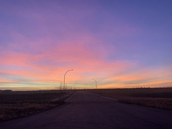 Road by street against sky during sunset