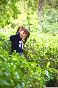 Portrait of cute girl standing amidst plants