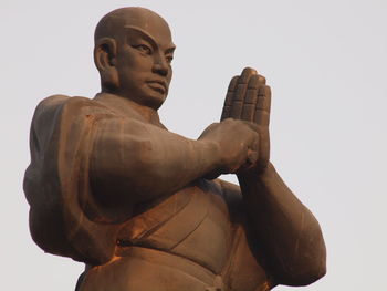 Low angle view of monk statue against sky