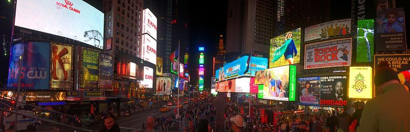 Panoramic view of crowd on city street at night