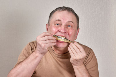 Portrait of man eating food against white background