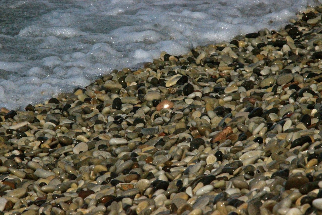 HIGH ANGLE VIEW OF PEBBLES ON BEACH