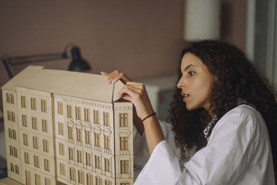 Focused female design professional preparing building model while working at office