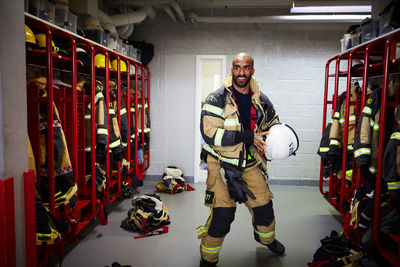 Male firefighter holding work helmet in locker room at fire station