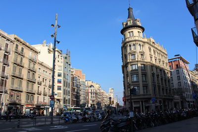 Cars on city street by buildings against sky