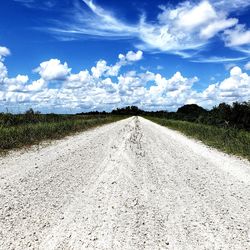 Road amidst field against sky