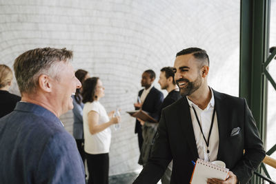 Cheerful businessmen discussing during networking event at convention center