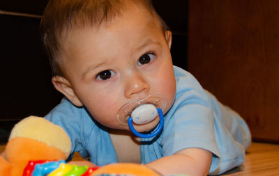 Portrait of cute boy with pacifier by toys