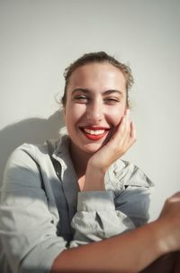 Portrait of a smiling young woman against wall