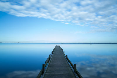 Pier over calm lake against sky