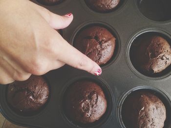 Cropped image of hand over brownie cupcakes in baking tray