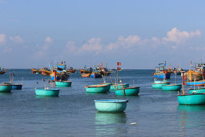 Blue boats moored in sea against sky