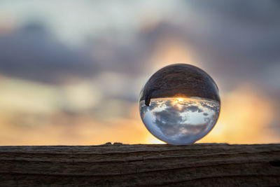 Close-up of crystal ball on railing against sky