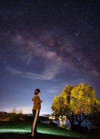 Man standing by tree against sky at night