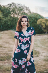 Portrait of beautiful young woman standing on field