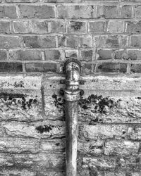 Close-up of faucet against brick wall