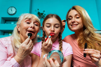 Cute girl applying lipstick with parents