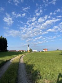 Road amidst field against sky