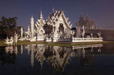 Panoramic view of temple by lake against sky
