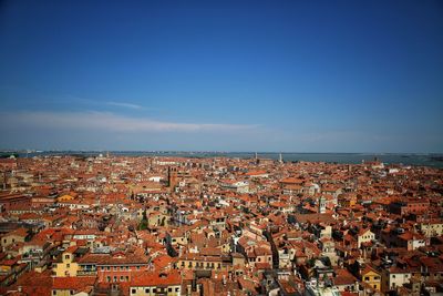 Aerial view of town by sea against blue sky