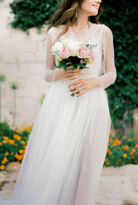 Midsection of bride holding bouquet