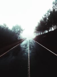 Road amidst trees against clear sky