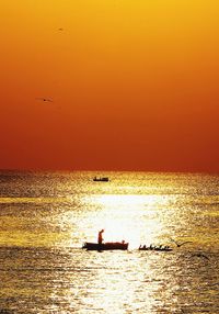 Birds flying over sea against sky during sunset